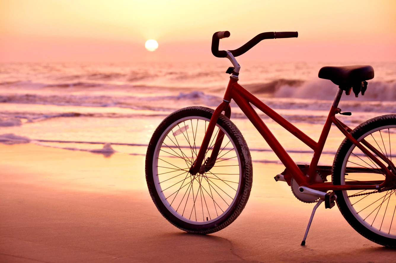 A cruiser bicycle on the sand at sunrise
